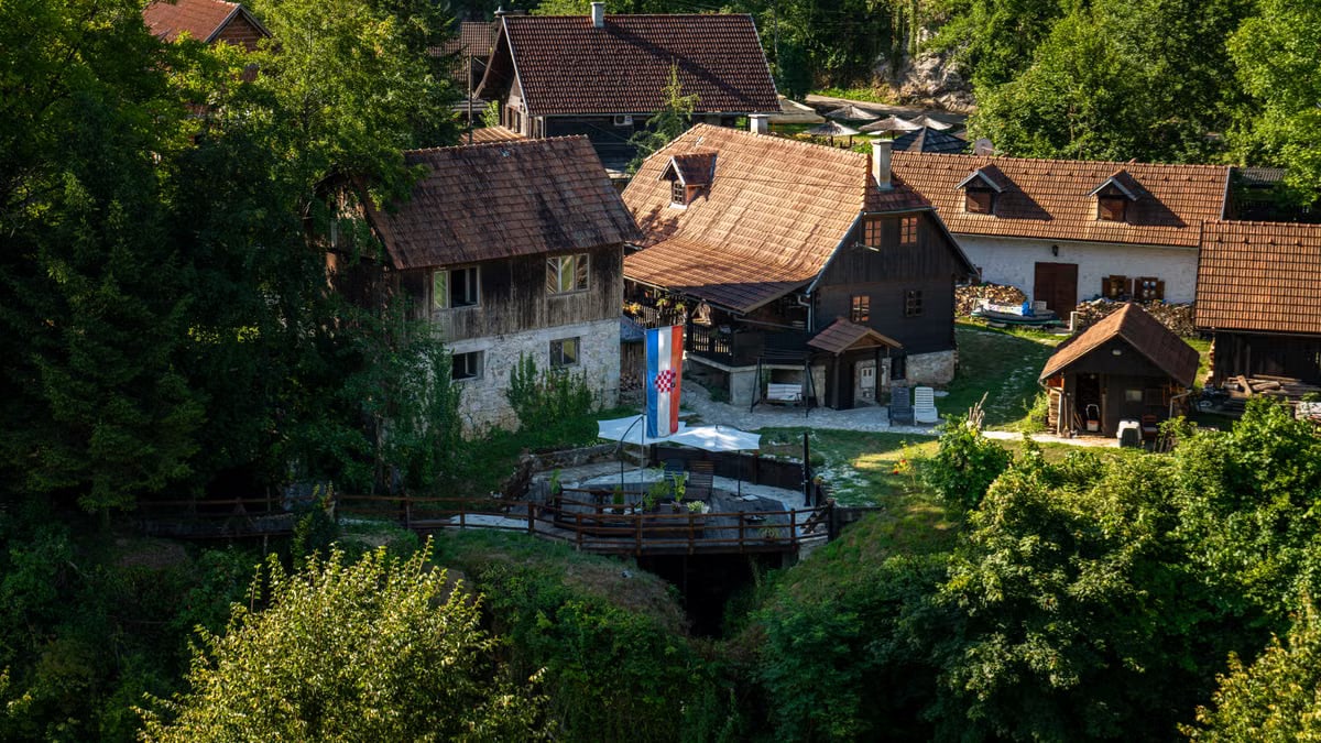Picturesque village scene in Slunj, Croatia, showcasing traditional architecture amidst lush greenery.
